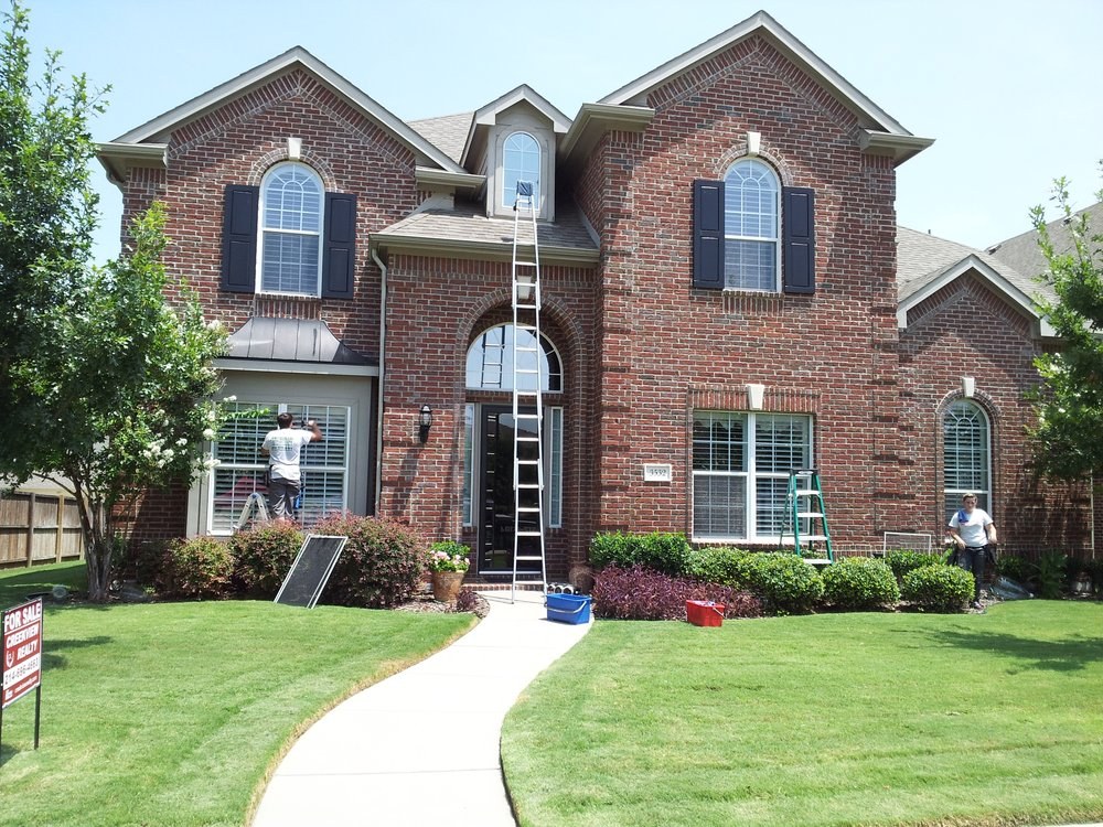 Metroplex crew cleaning the windows of a two-story brick home