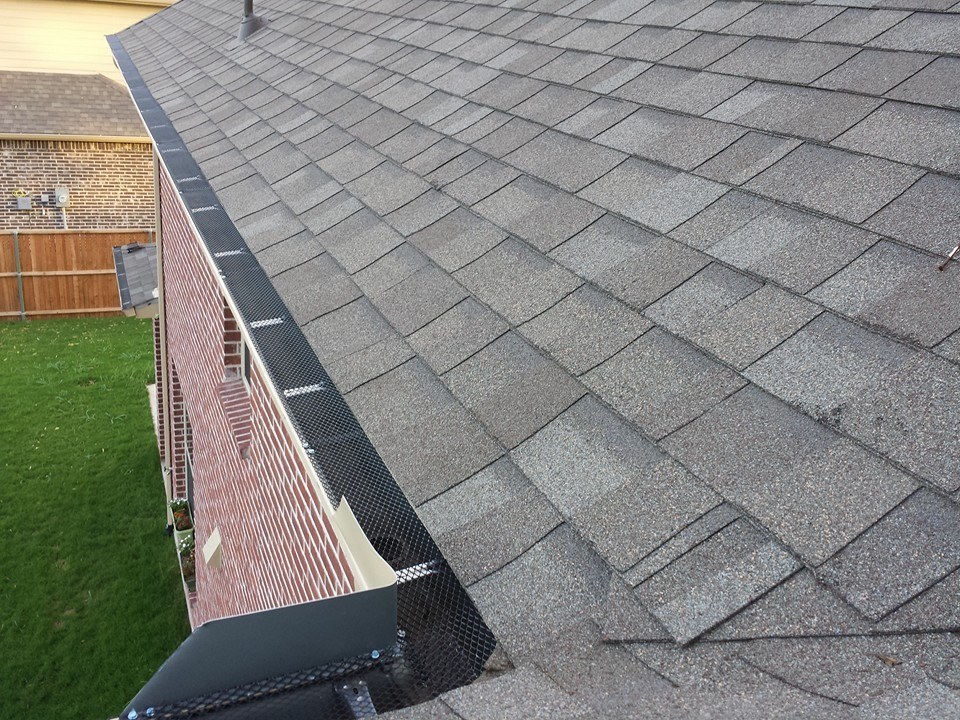 Gutter guard fitted along the roof edge of a brick home