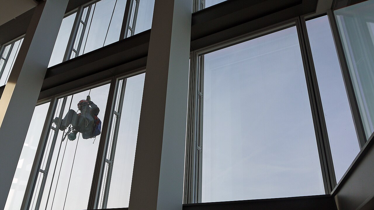 A window cleaner working on the glass facade of a tall building