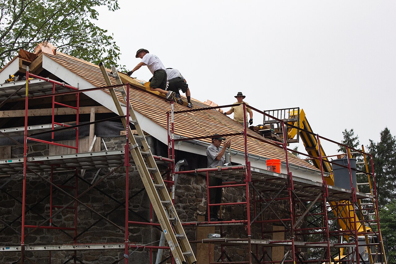 Workers installing new roofing and gutters on a home
